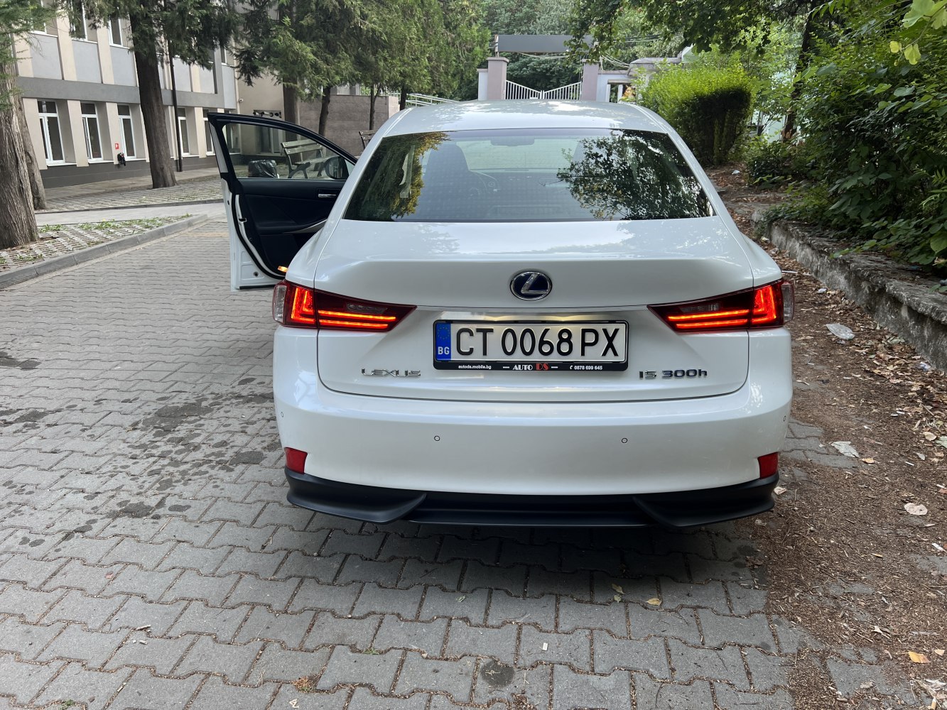 Rear view of a white sedan with LED tail lights and an open driver door