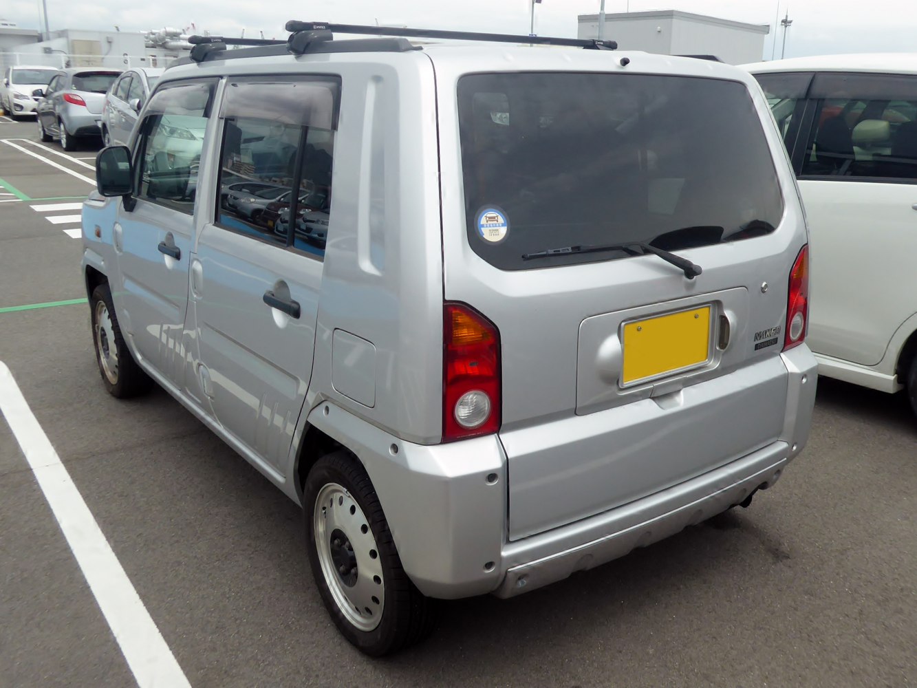 Compact boxy hatchback rear with roof rack and square tail lamps
