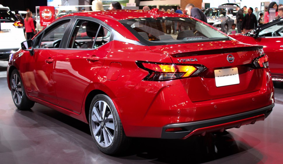 Rear and side view of a red compact sedan with modern taillights and alloy wheels