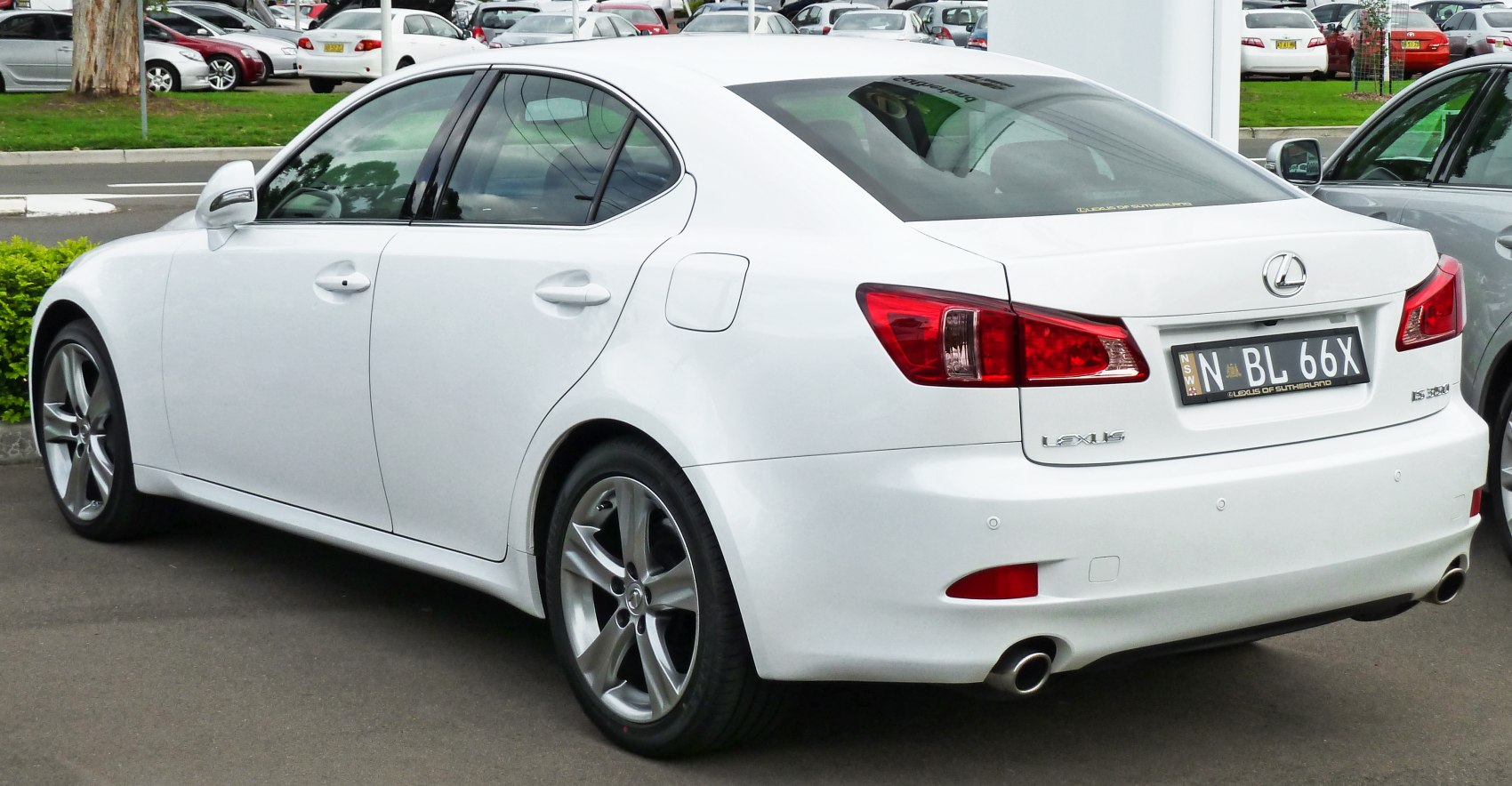 Rear-side view of white luxury sedan with alloy wheels and dual exhaust