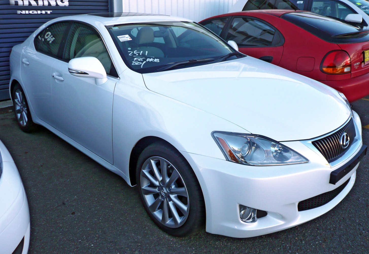 White sedan front side view with headlights and alloy wheels