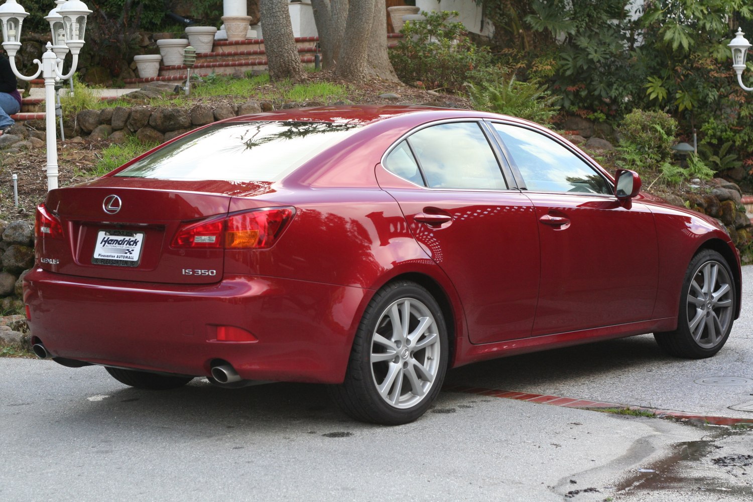 Rear and side view of red sedan with dual exhaust and alloy wheels