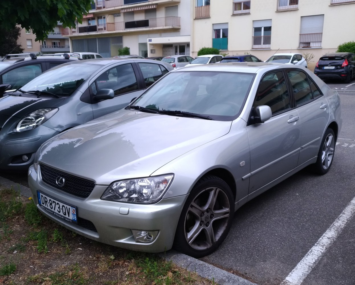 Silver sedan front side profile with distinctive headlights and alloy wheels