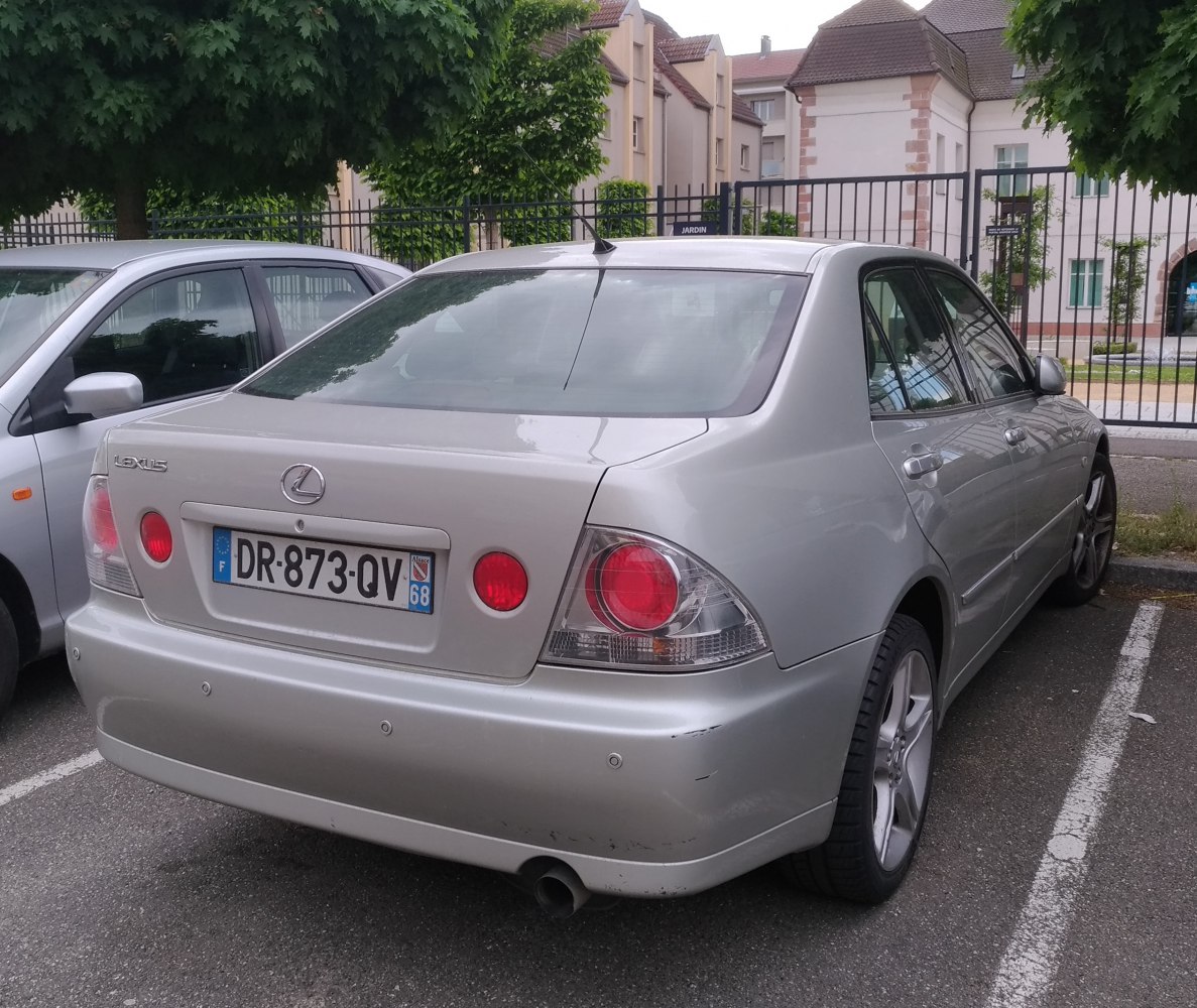 Rear view of silver sedan with round taillights and single exhaust