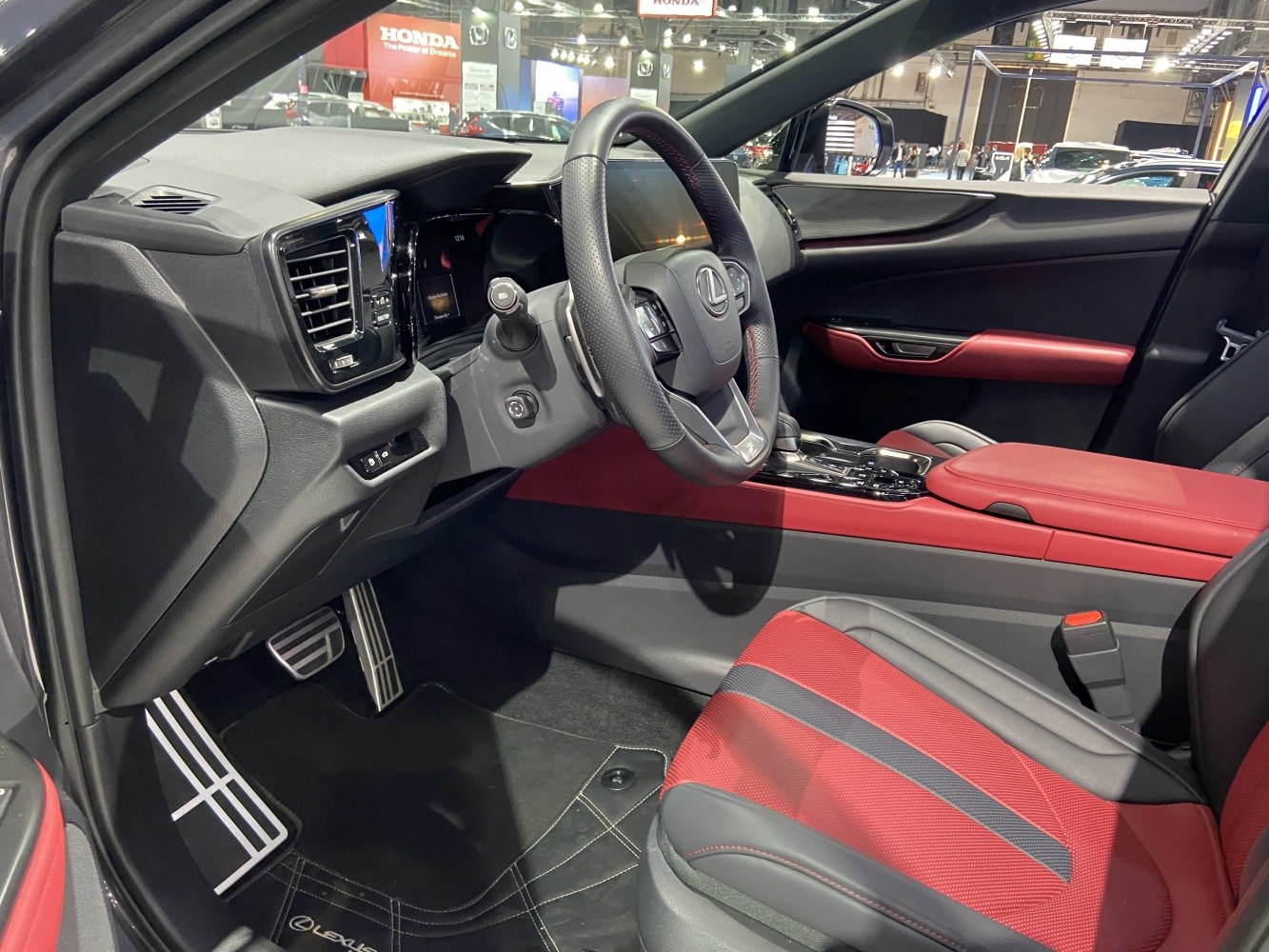 Luxury red and black interior with sporty steering wheel and modern infotainment.