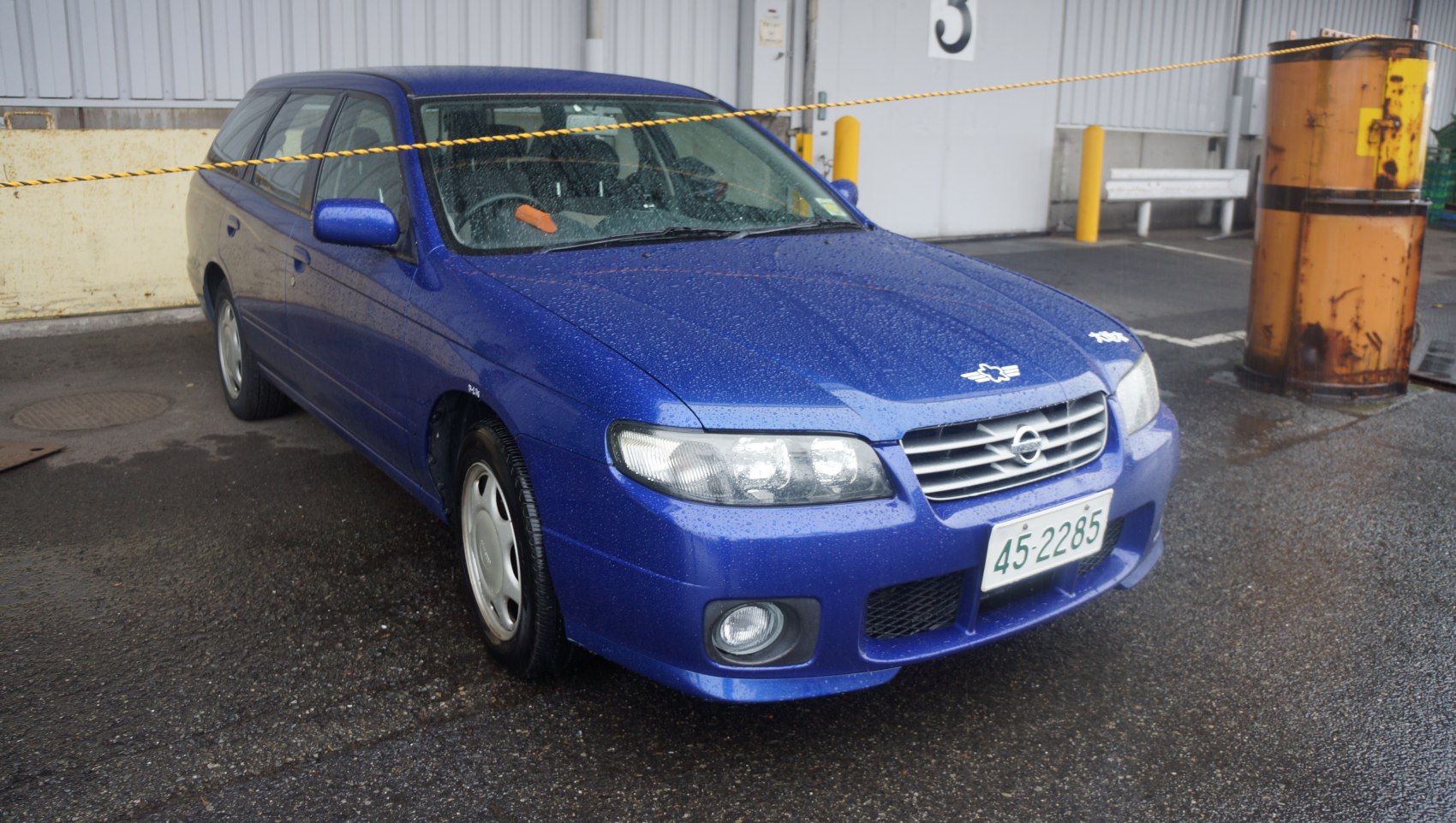 Front angle view of blue station wagon with headlights and grille