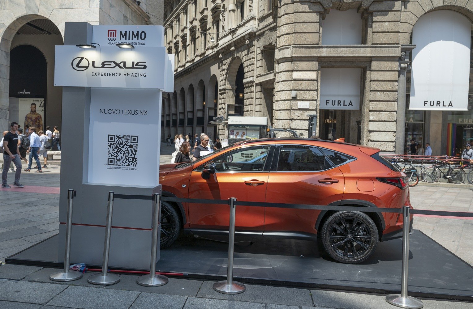 Side profile of a sleek orange SUV with black wheels on display