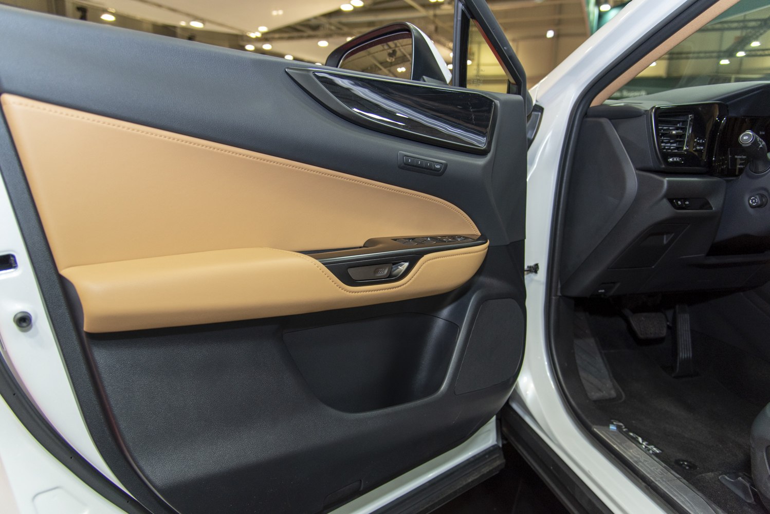 Luxury beige leather interior door panel with modern control buttons and speaker