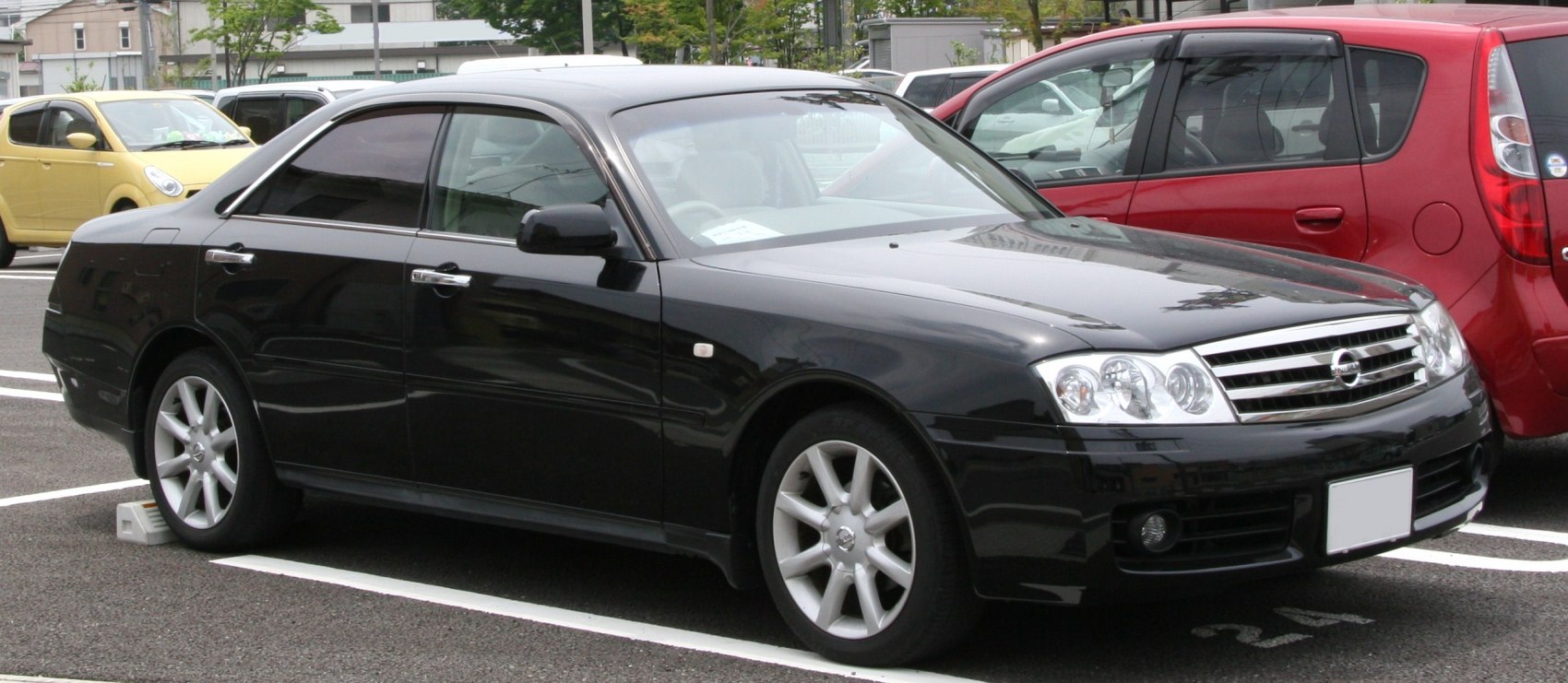 Side front view of black sedan with quad headlights and alloy wheels
