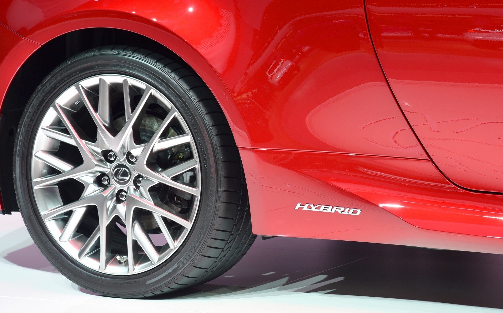 Close-up of alloy wheel and hybrid badge on red car side panel