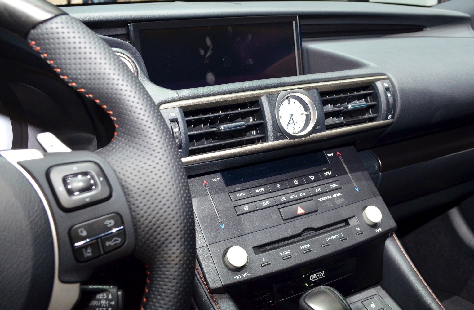 Close-up of dashboard with steering wheel, analog clock, air vents, and media controls