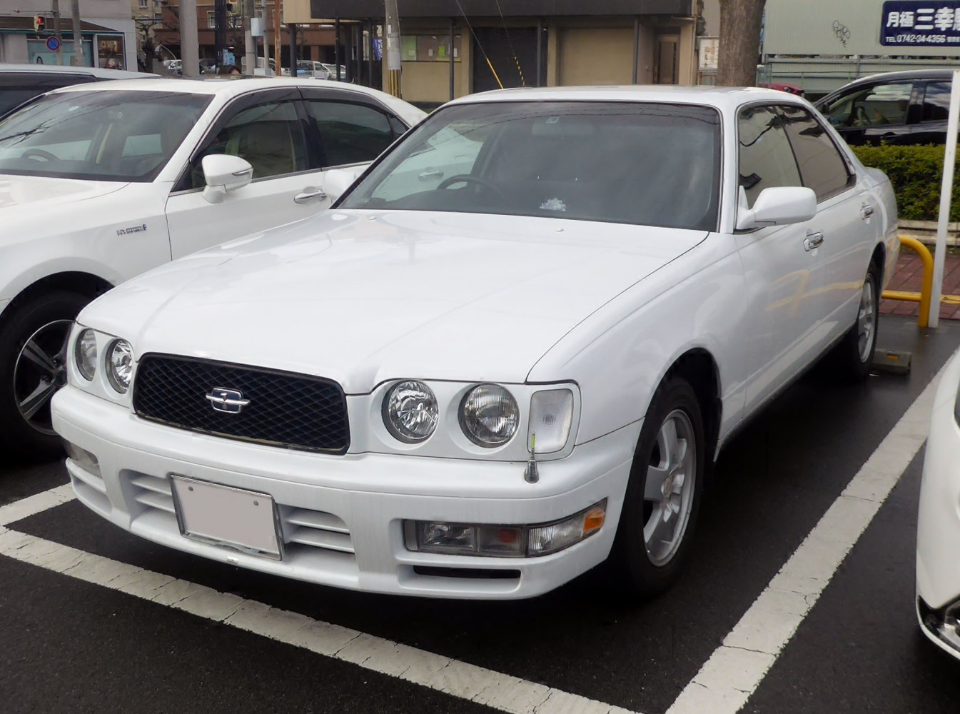 White sedan with dual round headlights and black mesh grille.