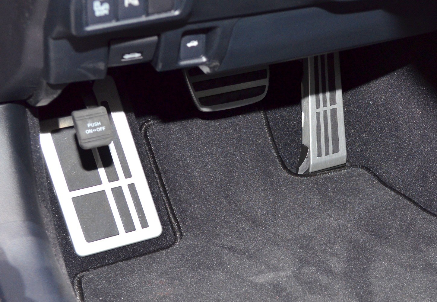 Metal foot pedals and parking brake pedal with carpeted floor