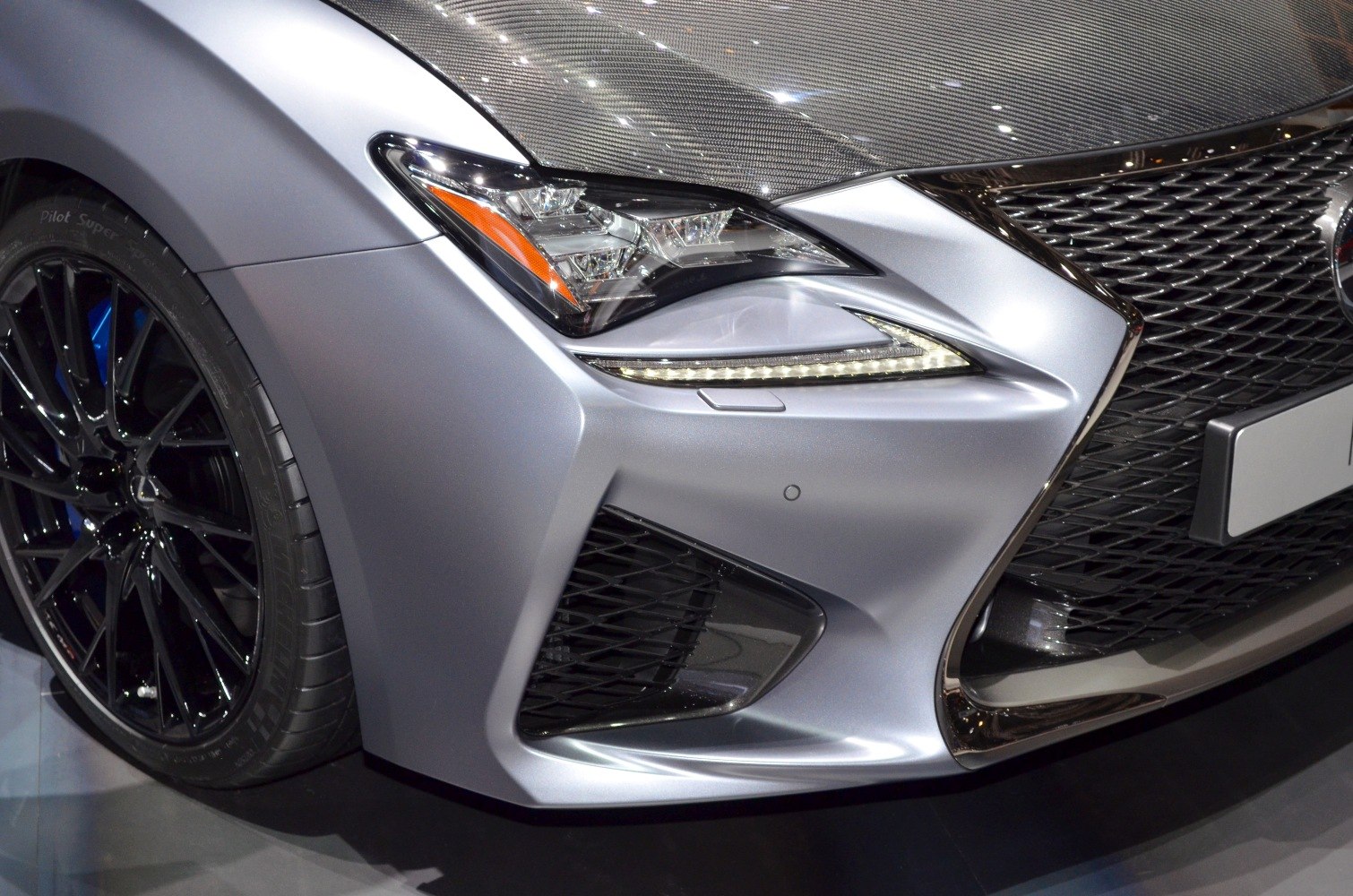 Close-up on front LED headlight, grille, and black alloy wheel