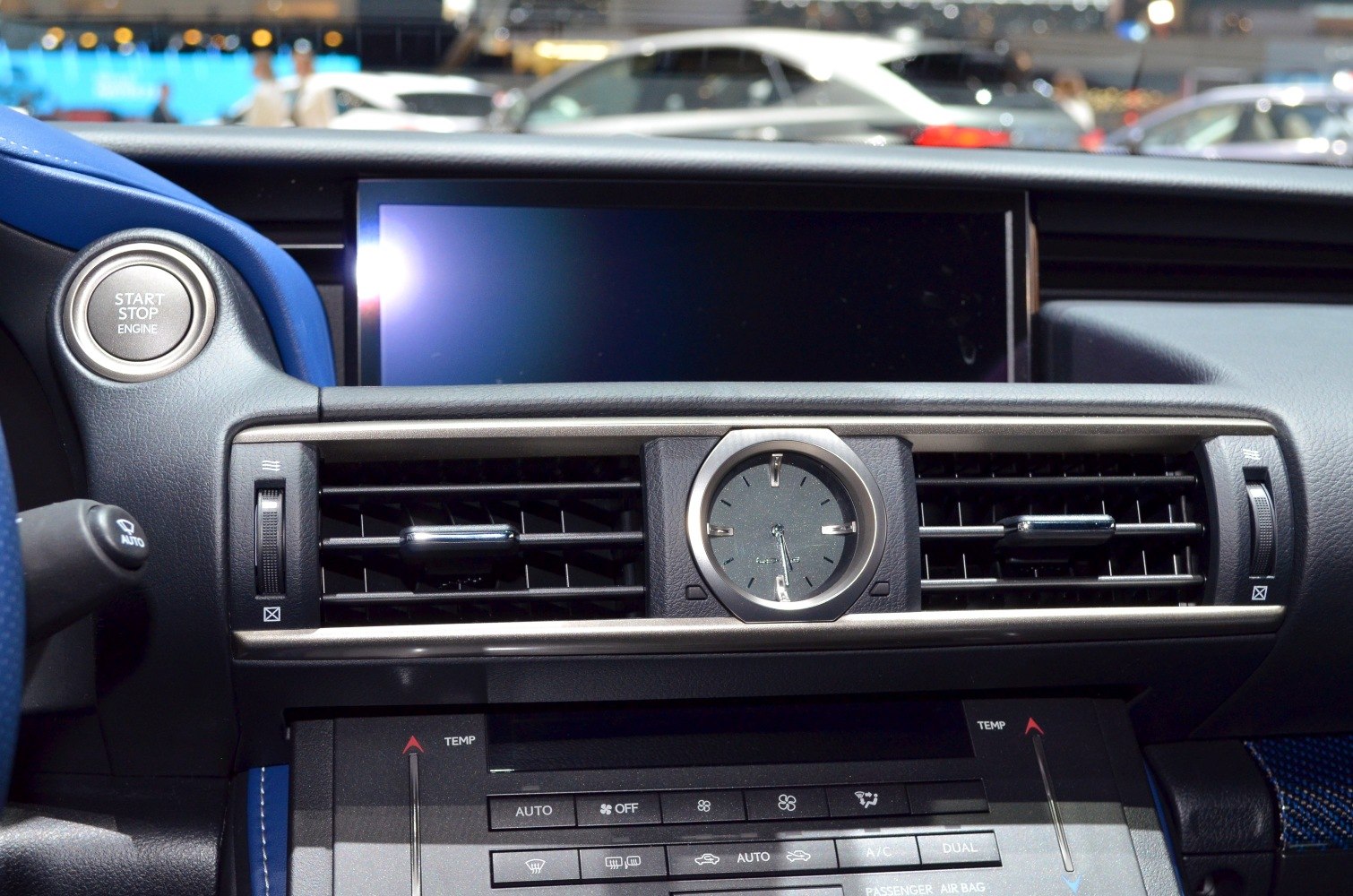 Analog clock, air vents, and engine start button in car dashboard