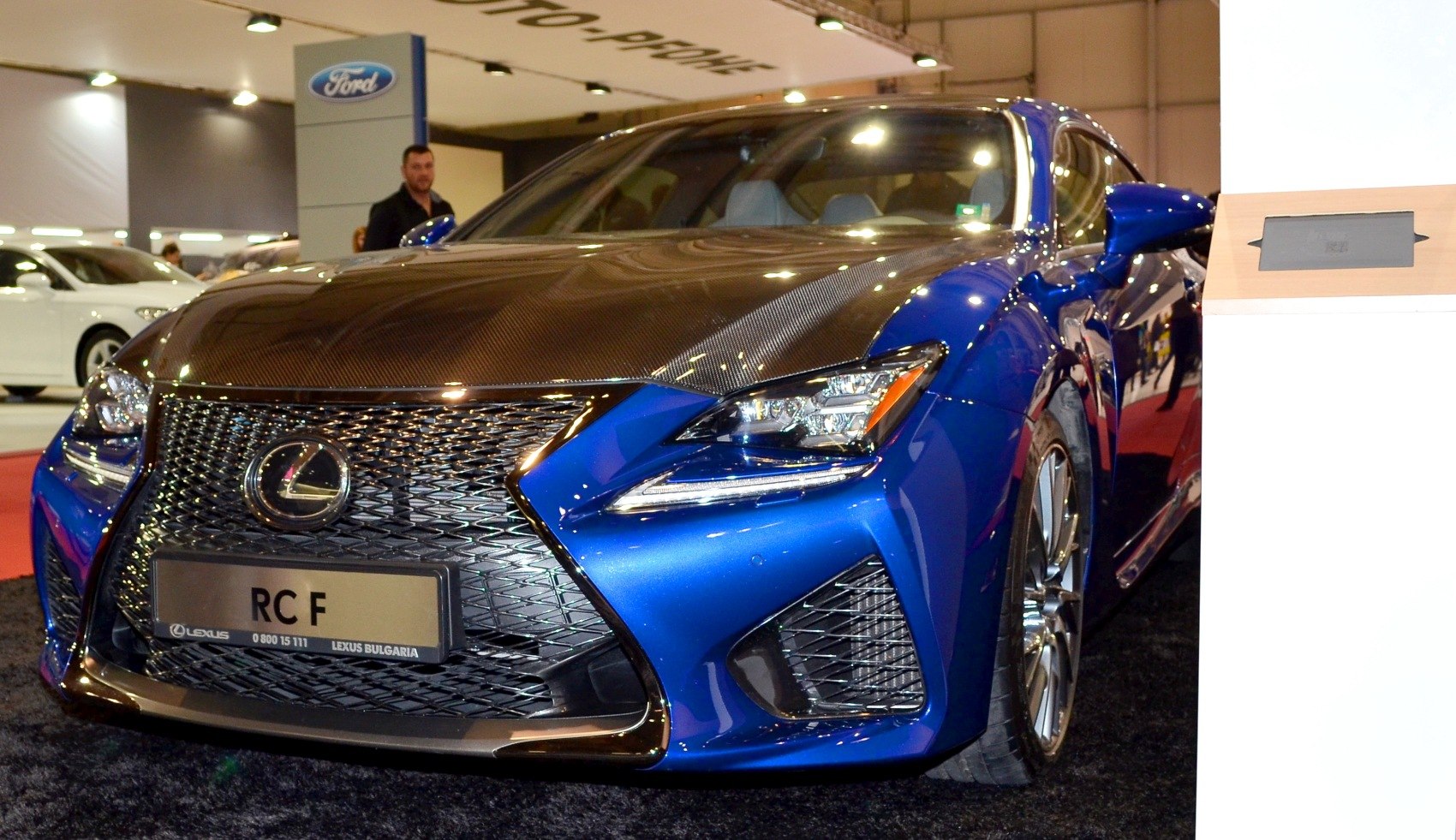 Front view of sporty blue coupe with carbon fiber hood and aggressive grille
