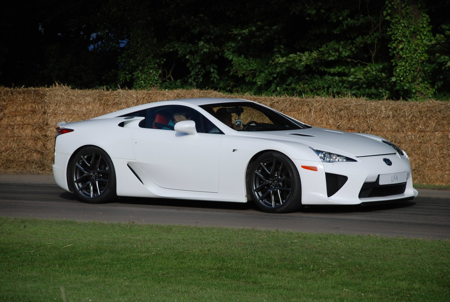Sleek aerodynamic side profile of a white sports coupe with dark alloy wheels.