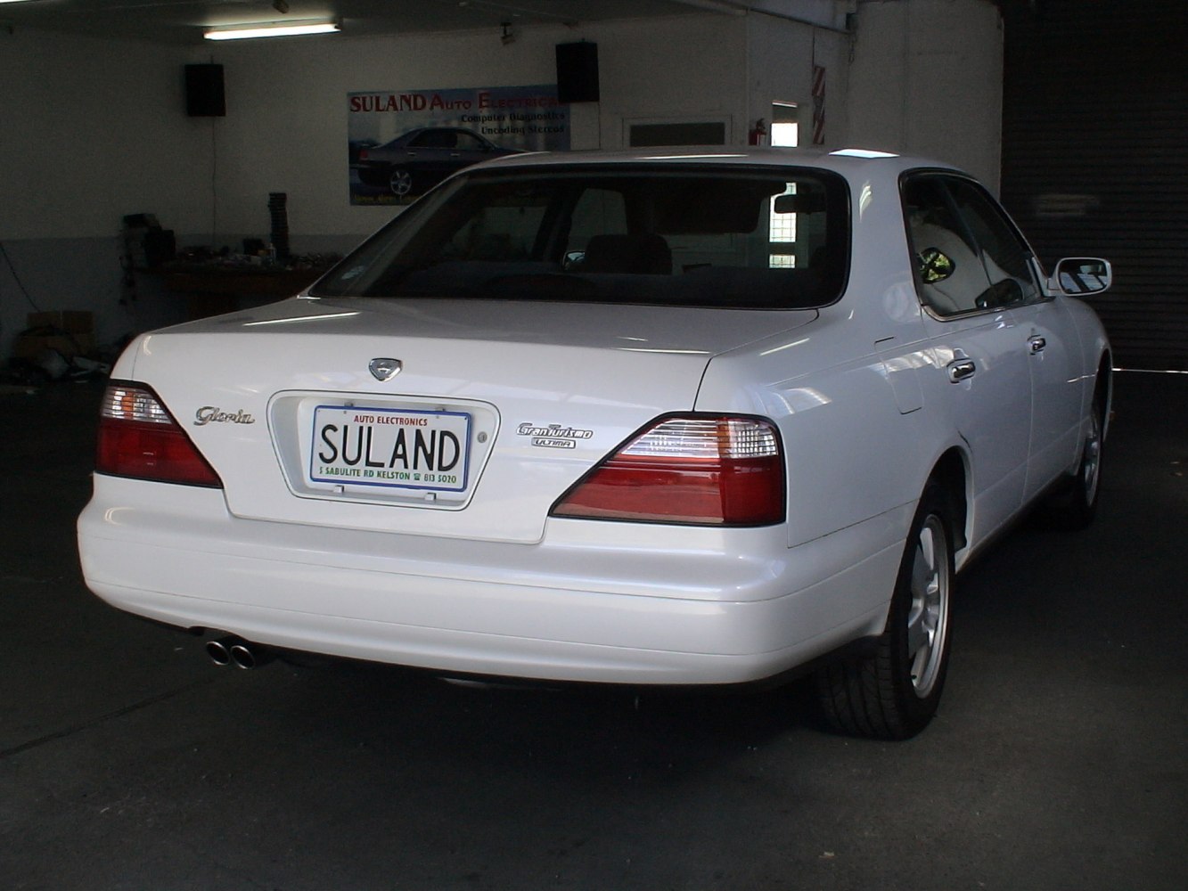 Rear view of a white sedan showcasing taillights and dual exhaust pipes