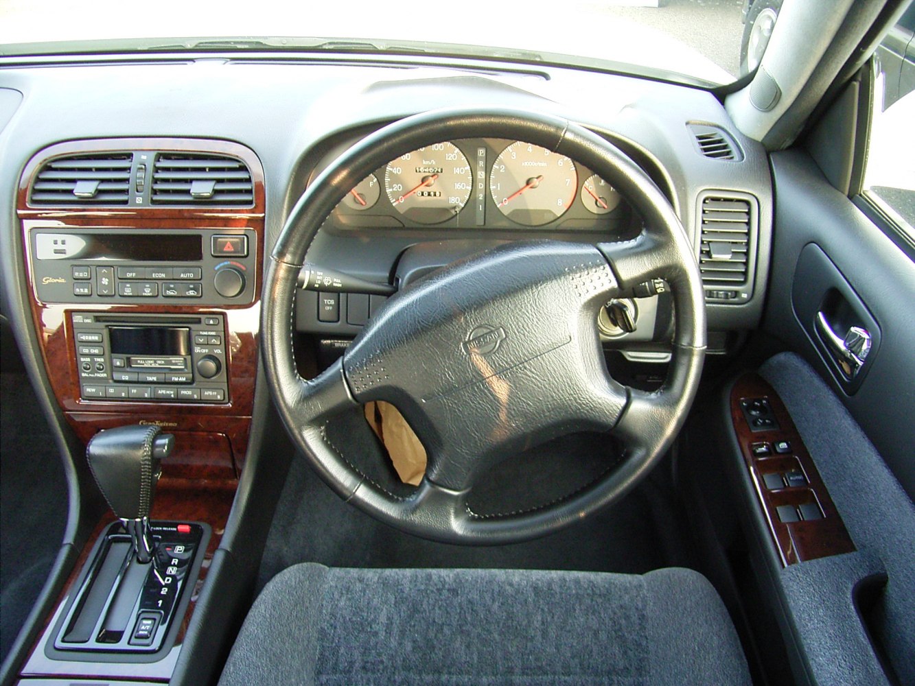 Classic car interior with dashboard, steering wheel, and wood-trimmed console