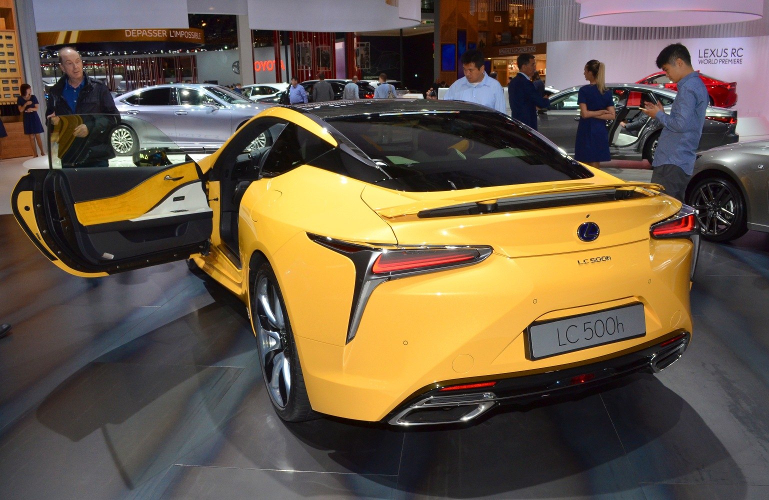 Yellow hybrid coupe rear view with open driver's side door and illuminated taillights