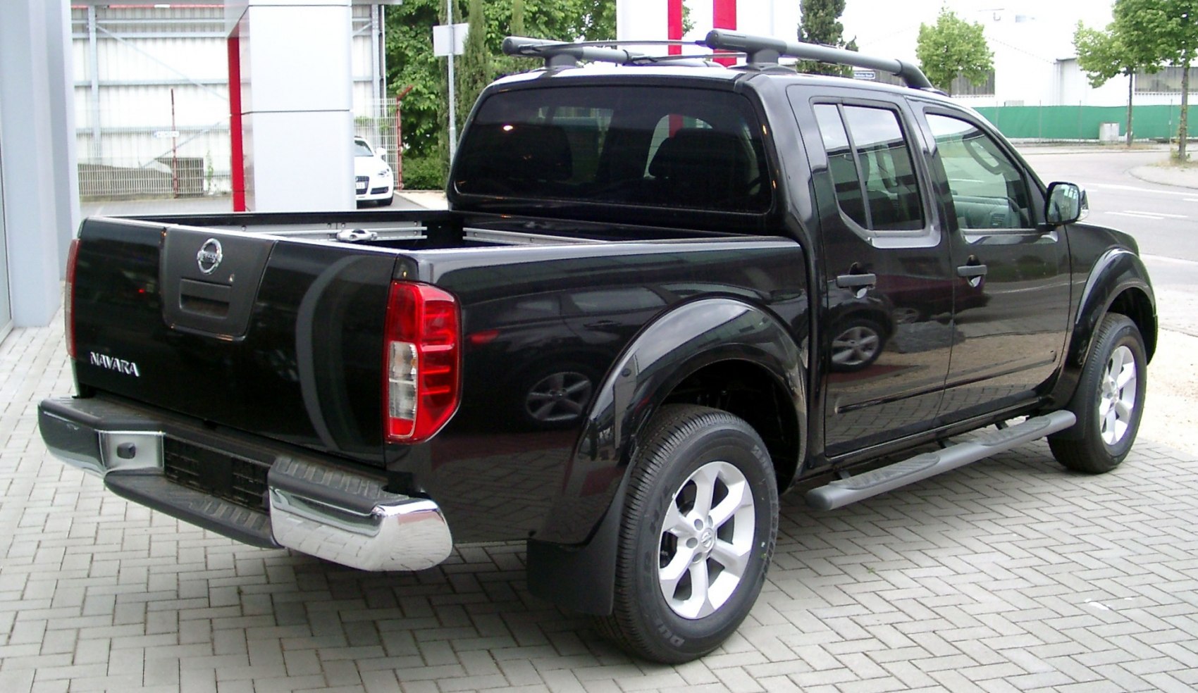 Rear side view of black pickup truck with roof rack and step rails