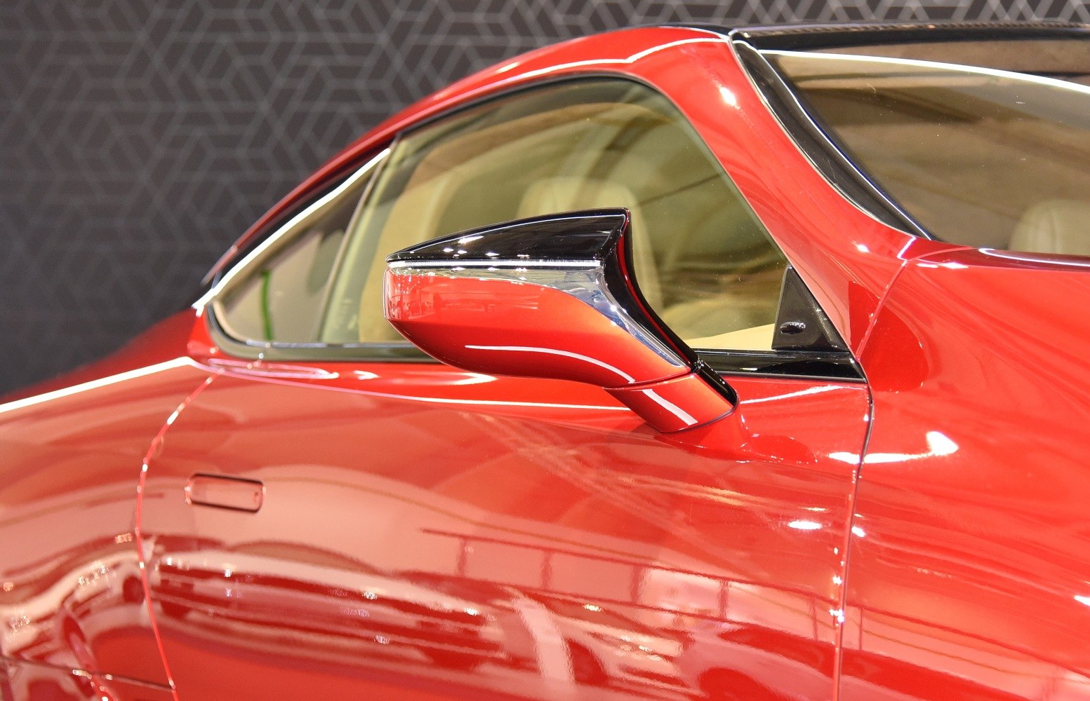 Close-up of sleek side mirror and door on red luxury coupe