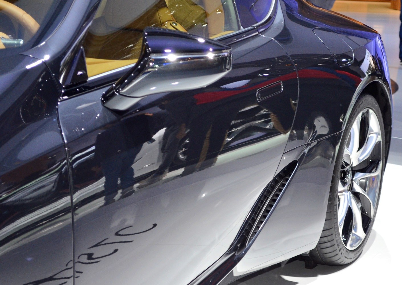 Close-up of black side mirror, rear wheel, and side air vent