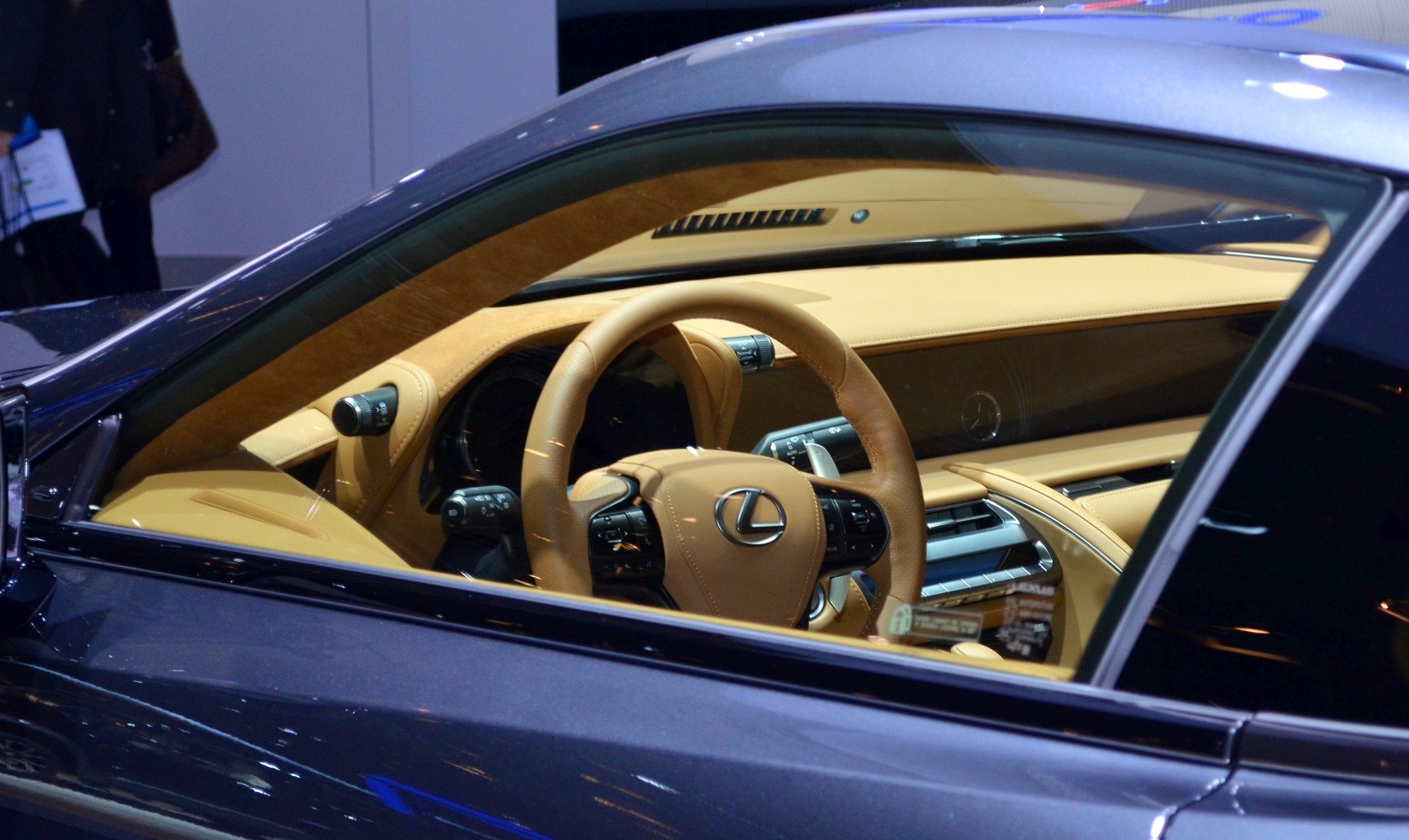 Leather steering wheel and detailed dashboard with controls in tan interior.