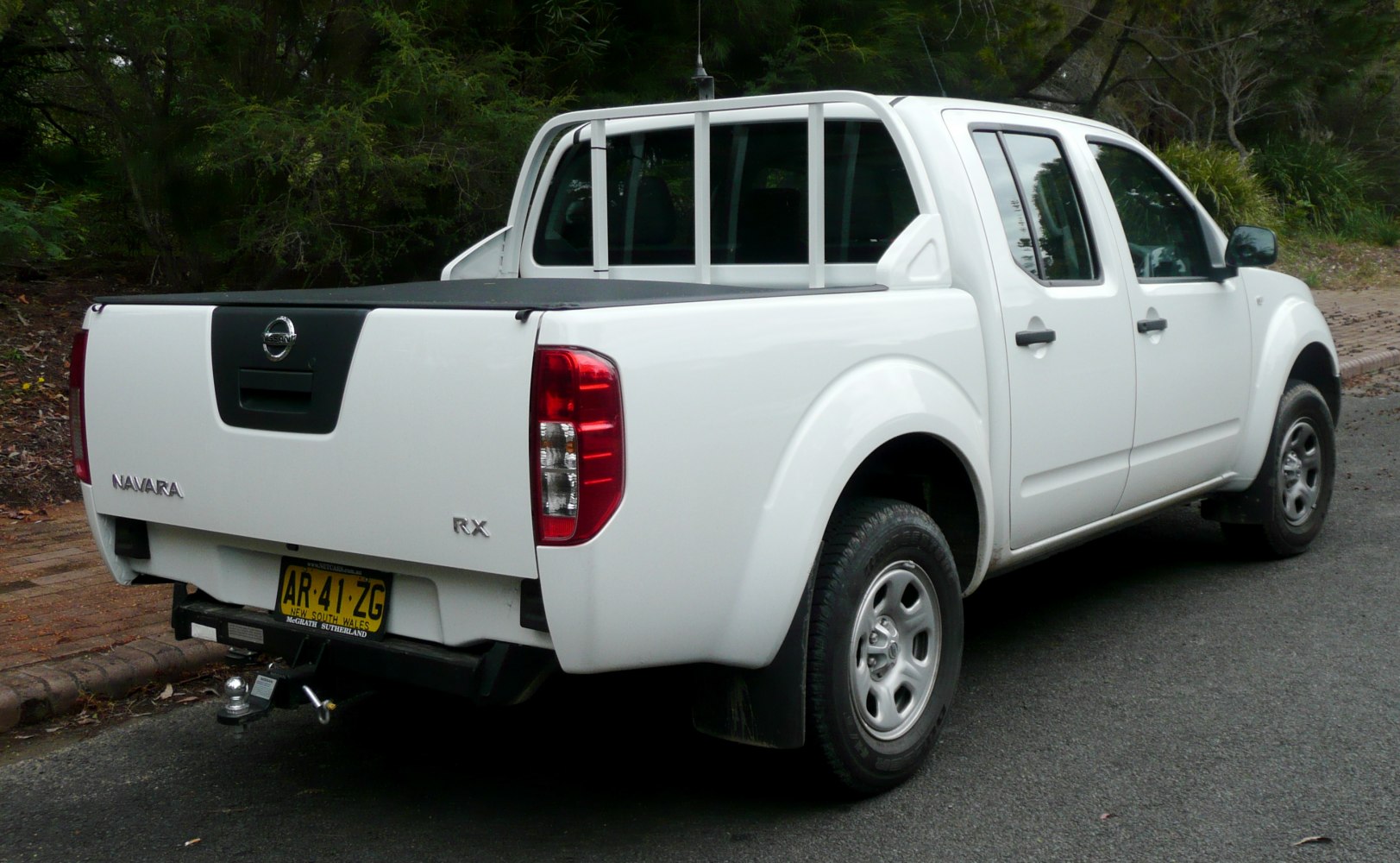 Rear and side view of a white pickup with utility bed and protective bars