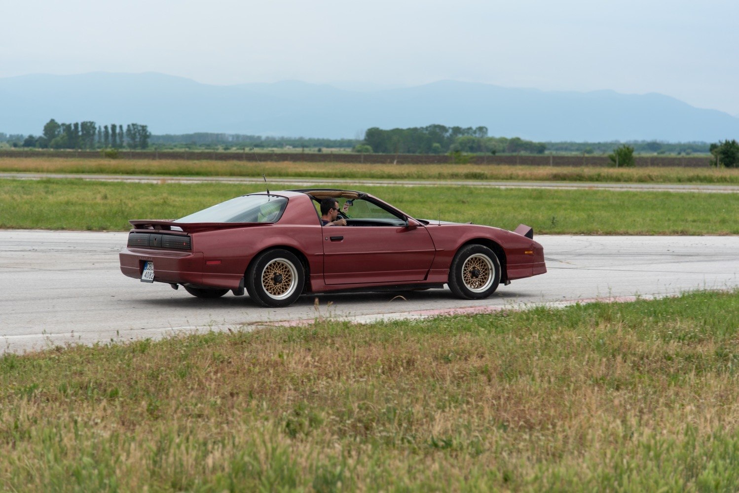 Rear-side view of a sports coupe with T-top roof and gold mesh wheels