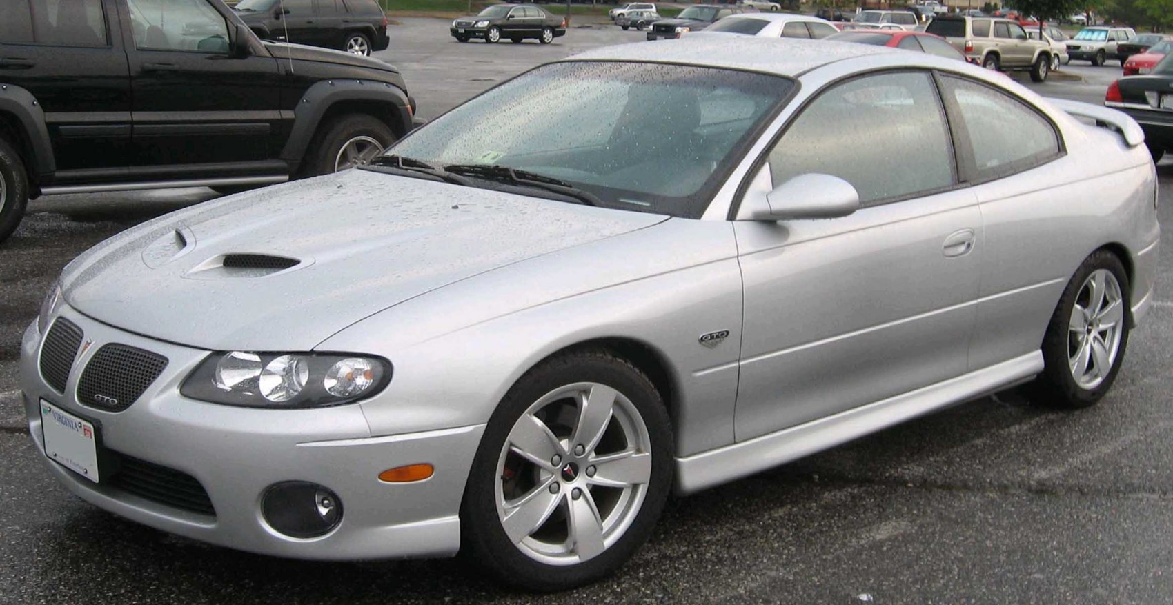 Silver coupe with hood scoop, rear spoiler, and alloy wheels.