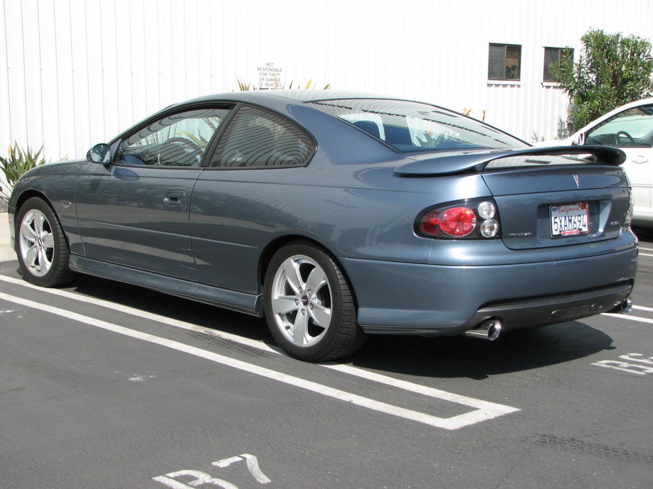 Rear side view with spoiler and dual exhaust in blue coupe