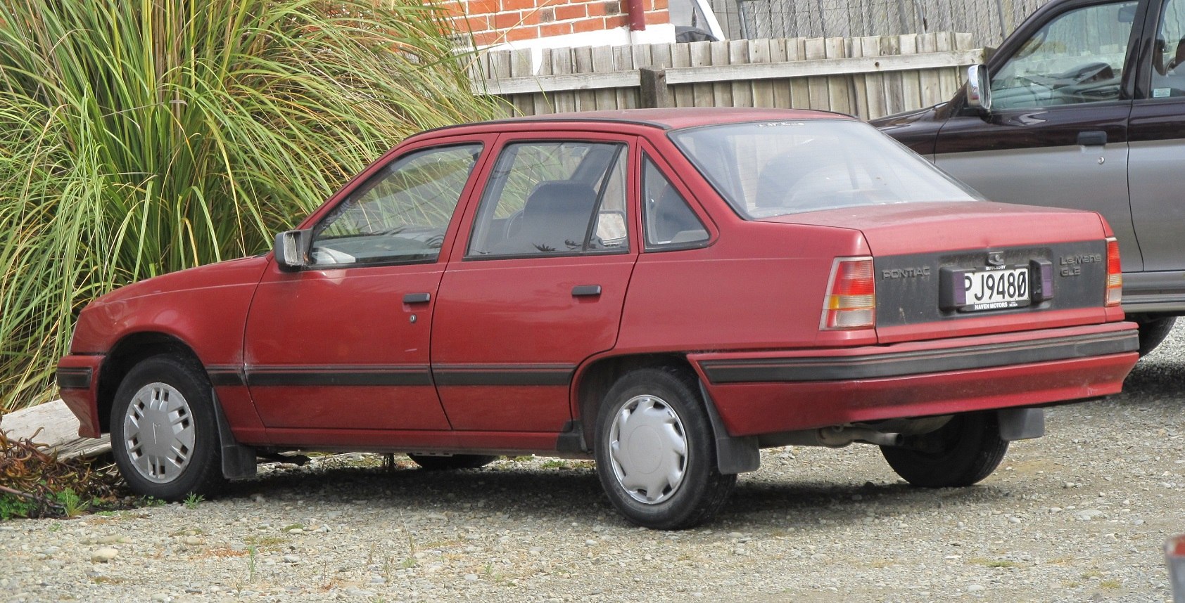Red four-door sedan rear side with hubcaps and black trim