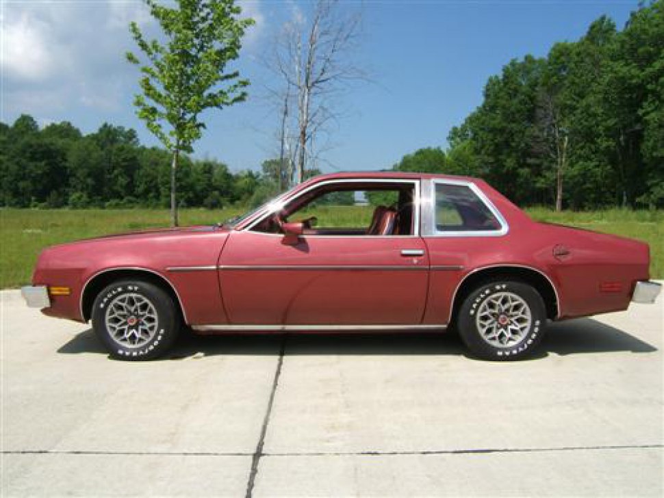 Two-door coupe side view with vintage alloy wheels and sleek design