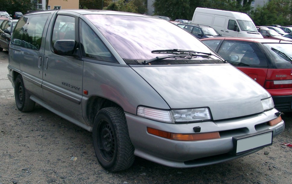 Front side view of a gray minivan with wraparound windshield and sliding door