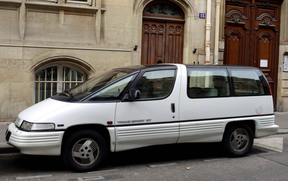 Side view of 1990s futuristic minivan with large windows and unique design.