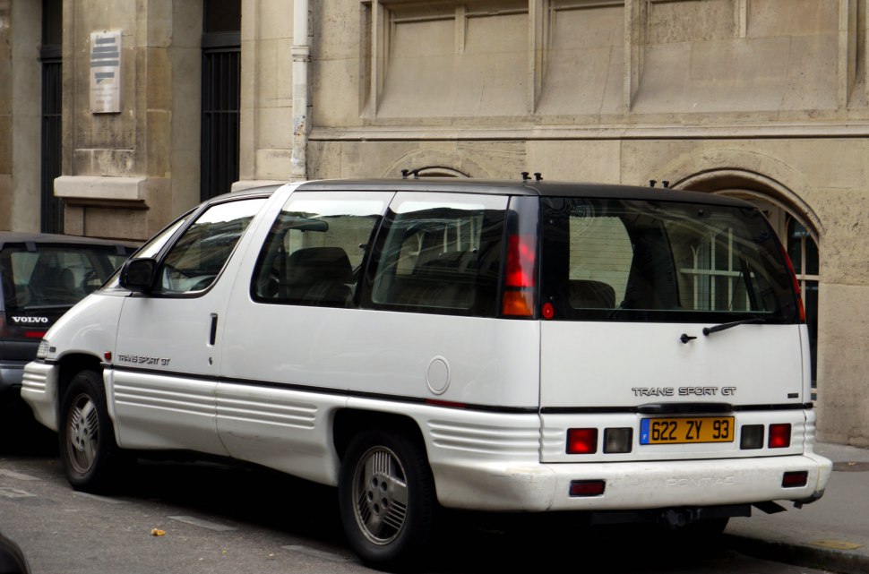 Rear side angle showing angular rear lights and large windows of minivan
