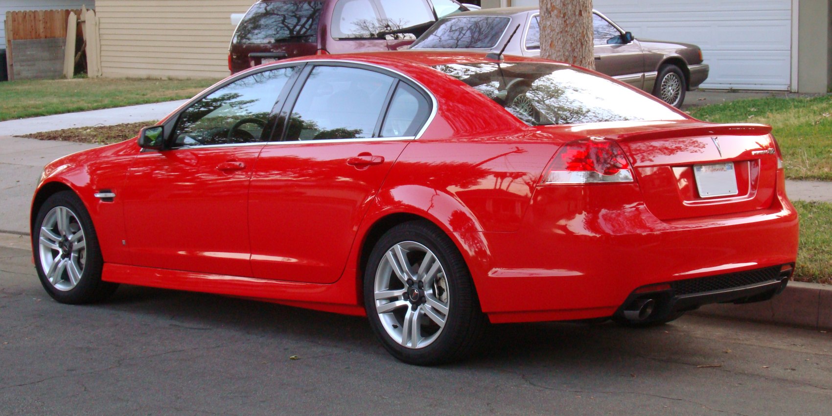 Rear side view of a sporty sedan with alloy wheels and red body