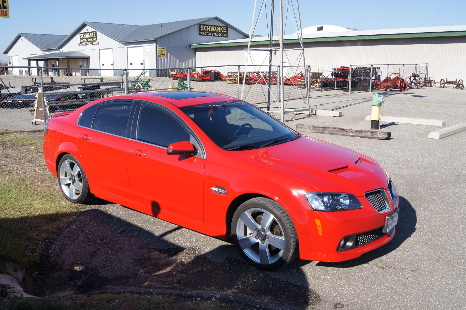 Red sedan with hood scoop and alloy wheels parked outdoors