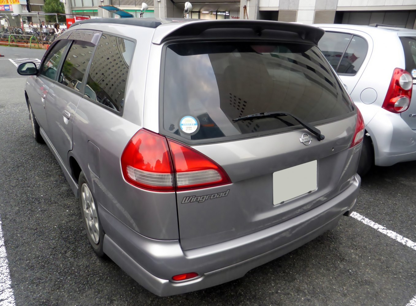 Rear view of silver station wagon with roof spoiler and prominent taillights