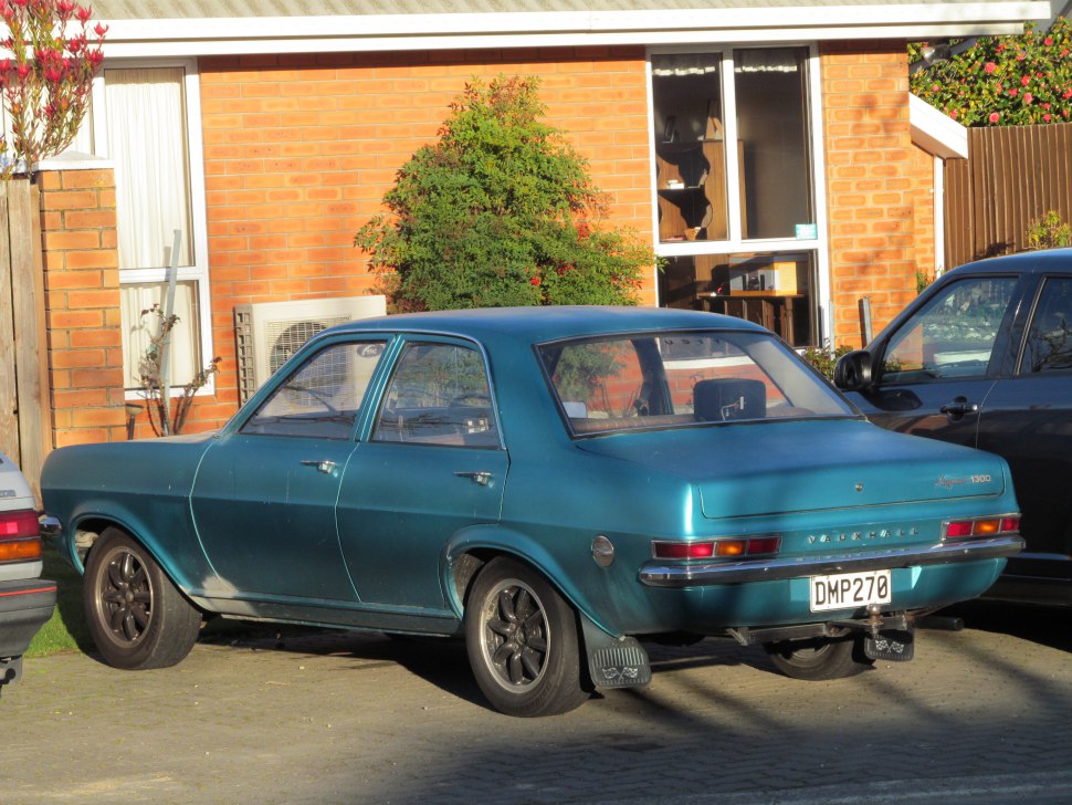 Rear view of a classic four-door vintage sedan with black alloy wheels and mudflaps