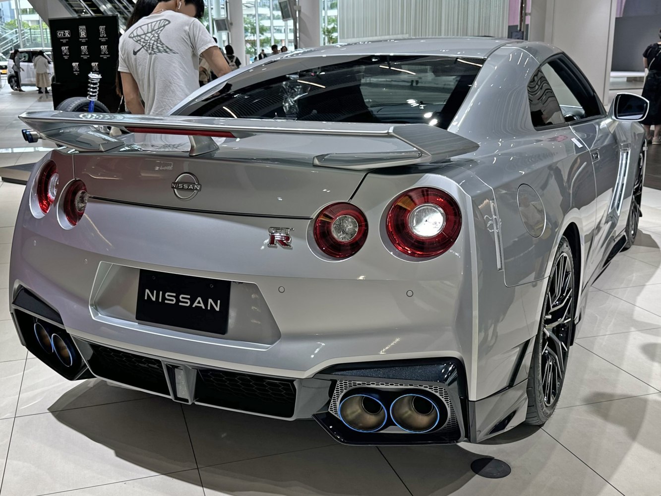 Rear view with round tail lights, quad exhaust tips, and rear wing spoiler.