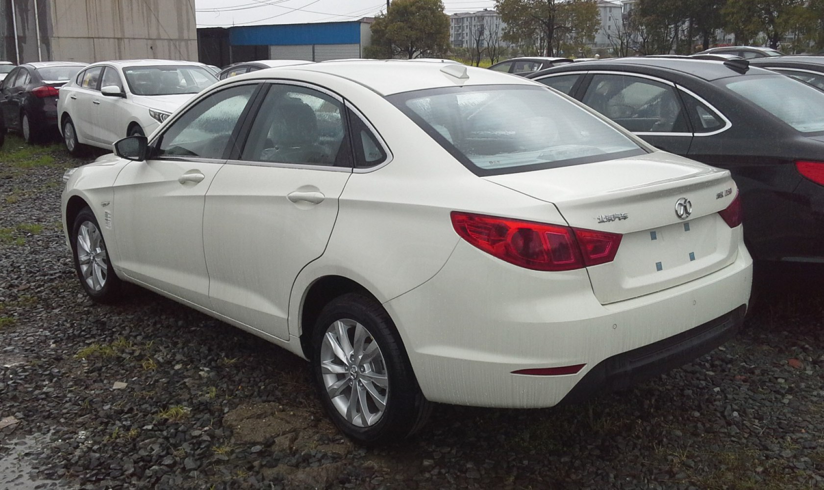 White mid-sized sedan with rear spoiler and alloy wheels