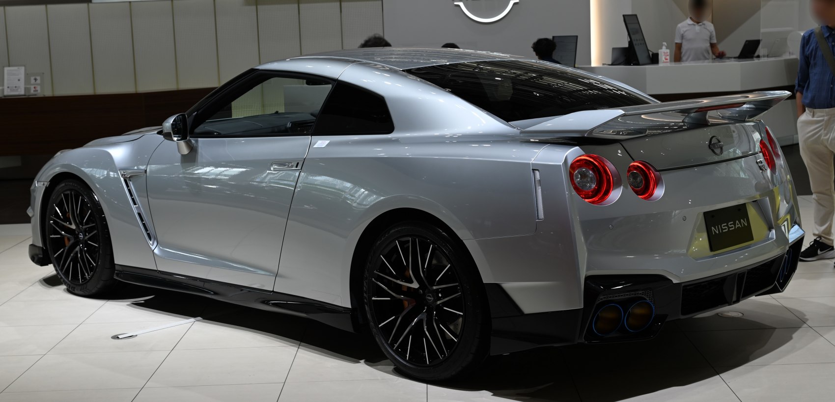 Rear side view of silver coupe with round taillights and rear wing spoiler