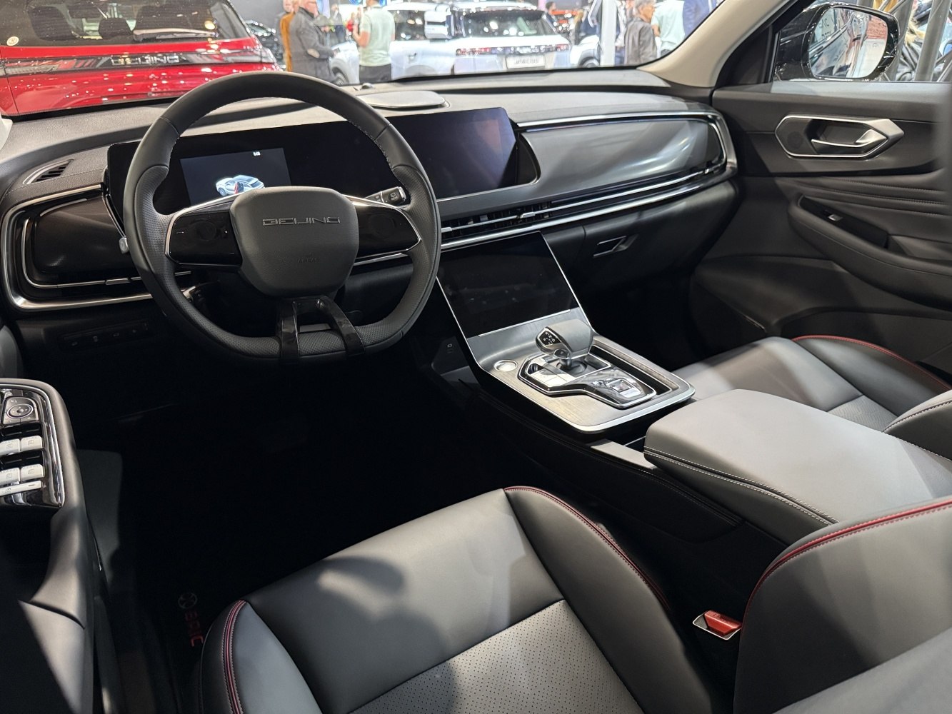 Digital dashboard and steering wheel with infotainment screen and gear selector.