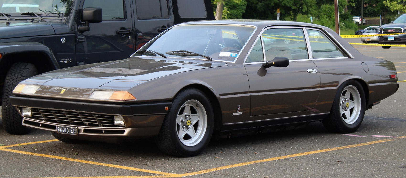 Front and side profile of vintage coupe with pop-up headlights and five-spoke wheels.