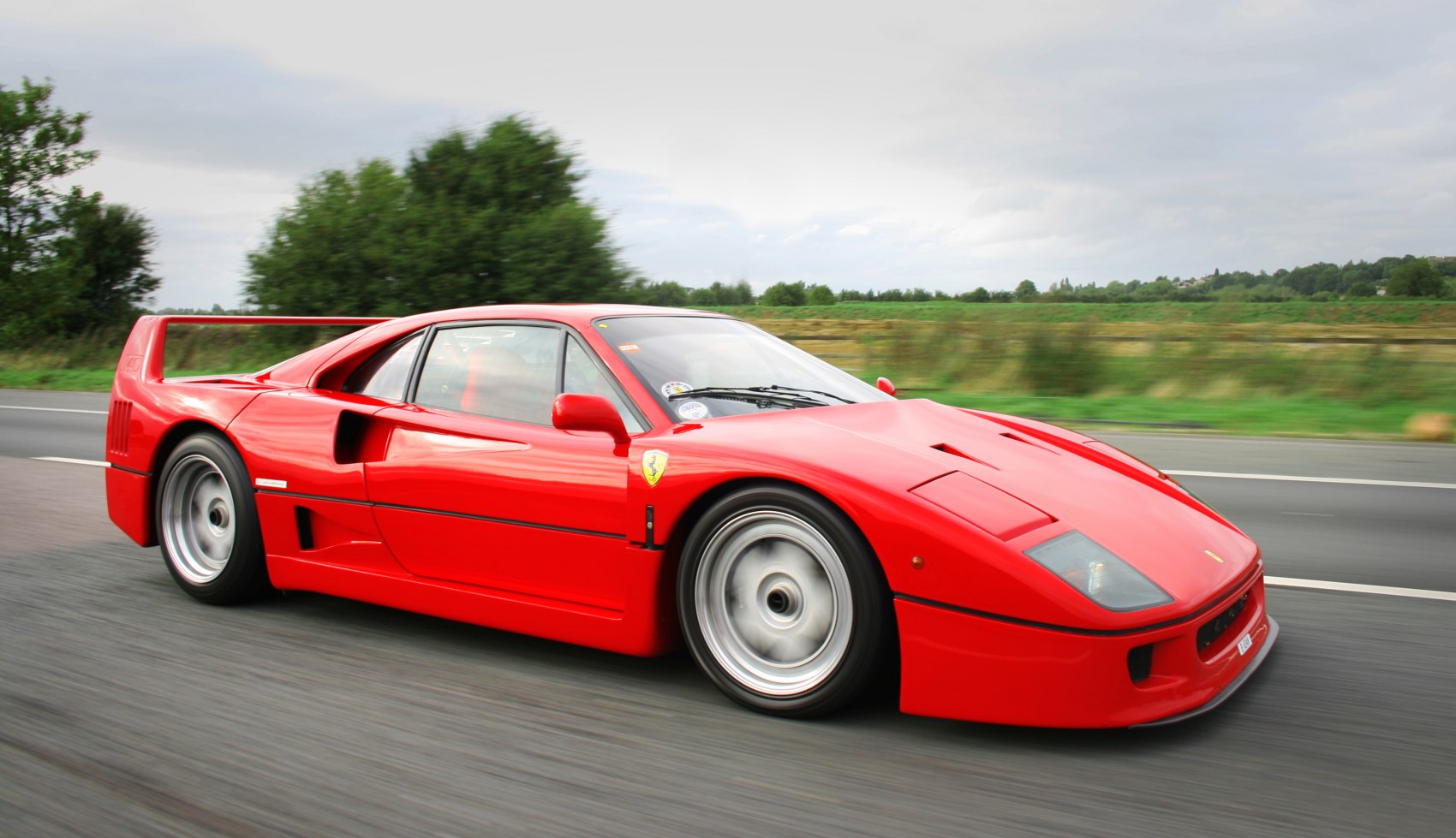 Red sports car with low front profile and large rear wing in motion