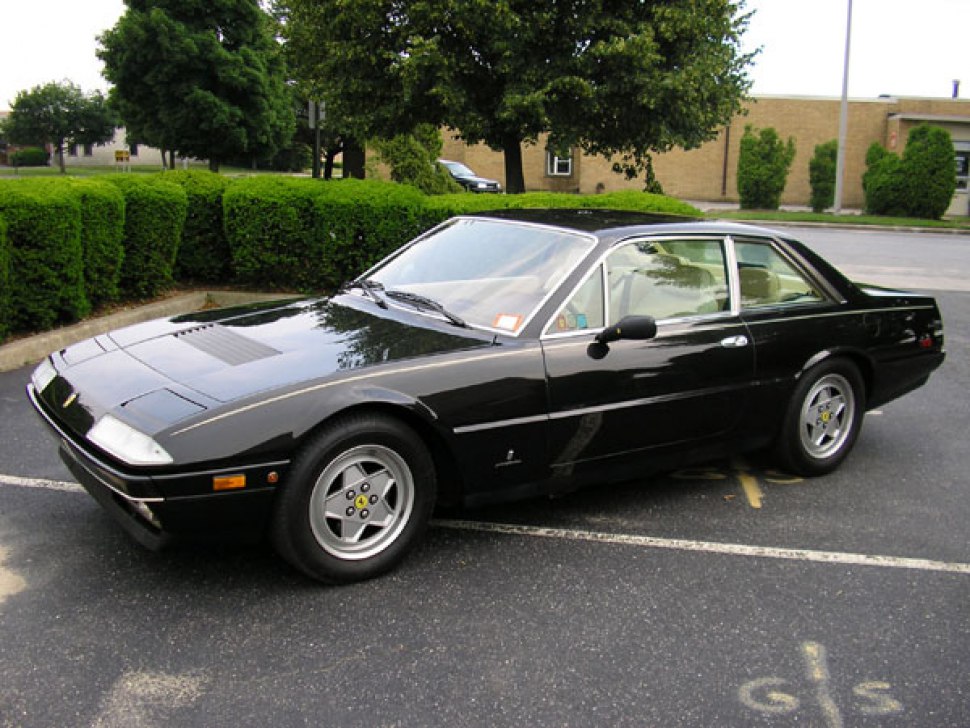 Black 1980s coupe with pop-up headlights and distinctive alloy wheels