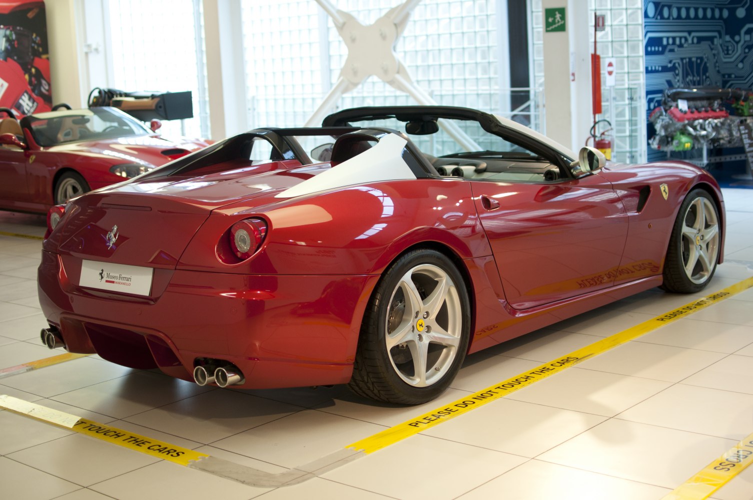 Convertible sports car rear with round taillights and dual exhaust pipes.