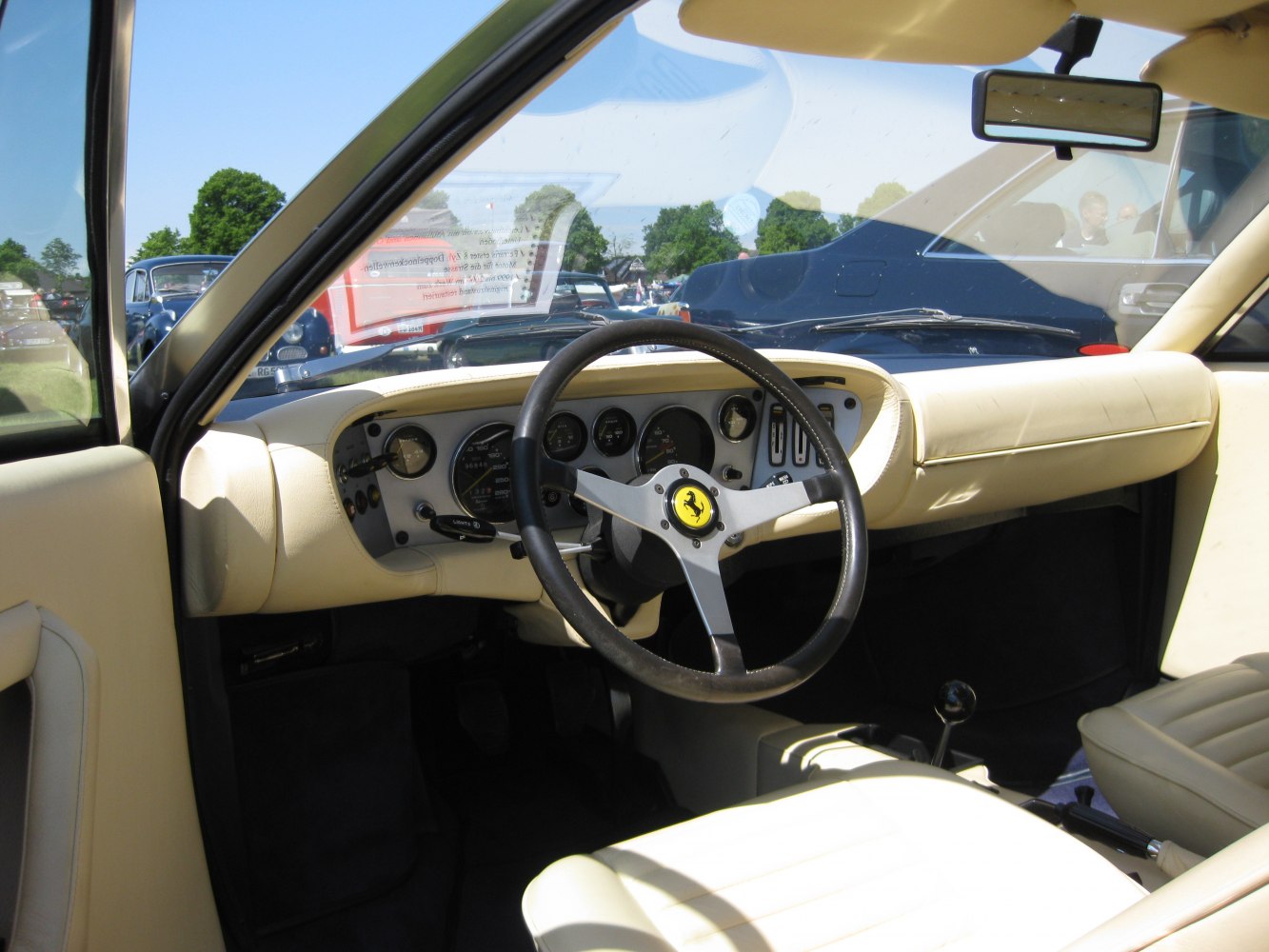 Beige interior featuring a sporty steering wheel with emblem and retro dashboard gauges.